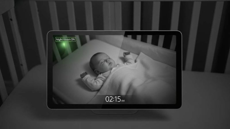 A modern 1080p baby monitor displaying a clear nighttime view of a sleeping infant in a crib with night vision activated