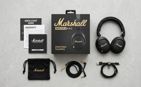 Marshall headphones resting on a wooden table next to a vinyl record player.